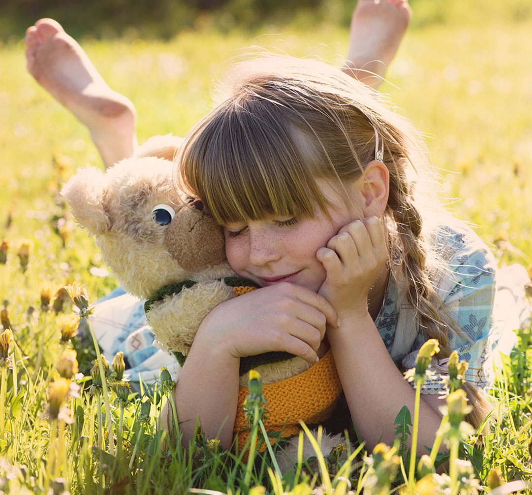 Girl Smiling and Holding Her Stuff Bear